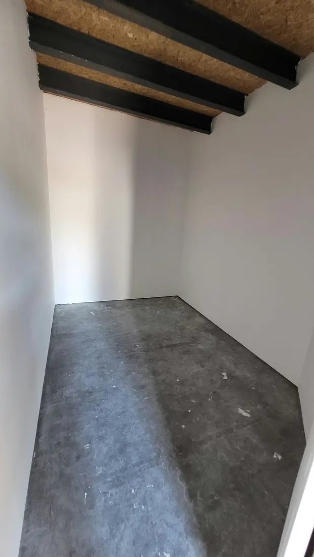 Box de stockage au rez-de-chaussée, murs blancs et sol en béton